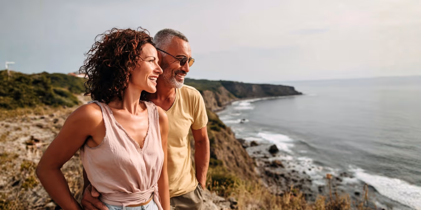A couple looking out over the ocean from a coastal overlook.