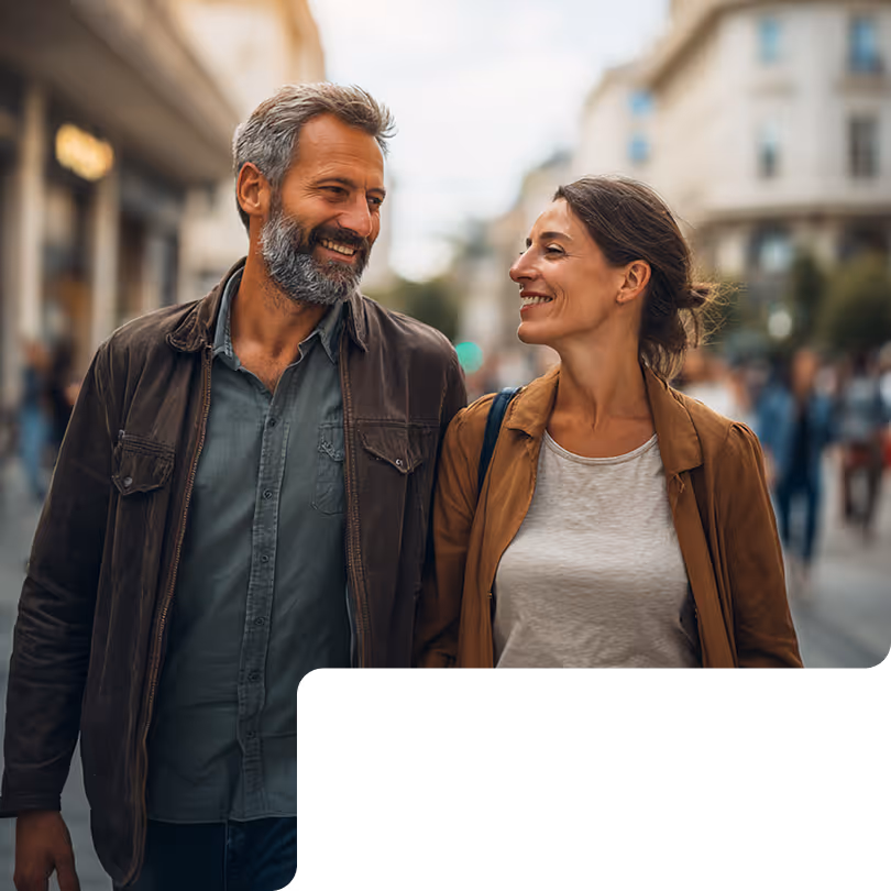 Smiling middle-aged man with gray beard and woman walking together on busy city street.